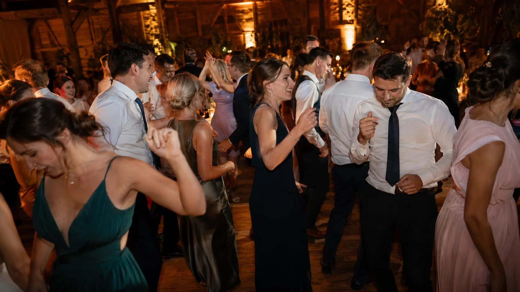 Hochzeits-Tanzfläche abends mit warmem Licht und tanzenden Gästen in eleganter Eventlocation bei München