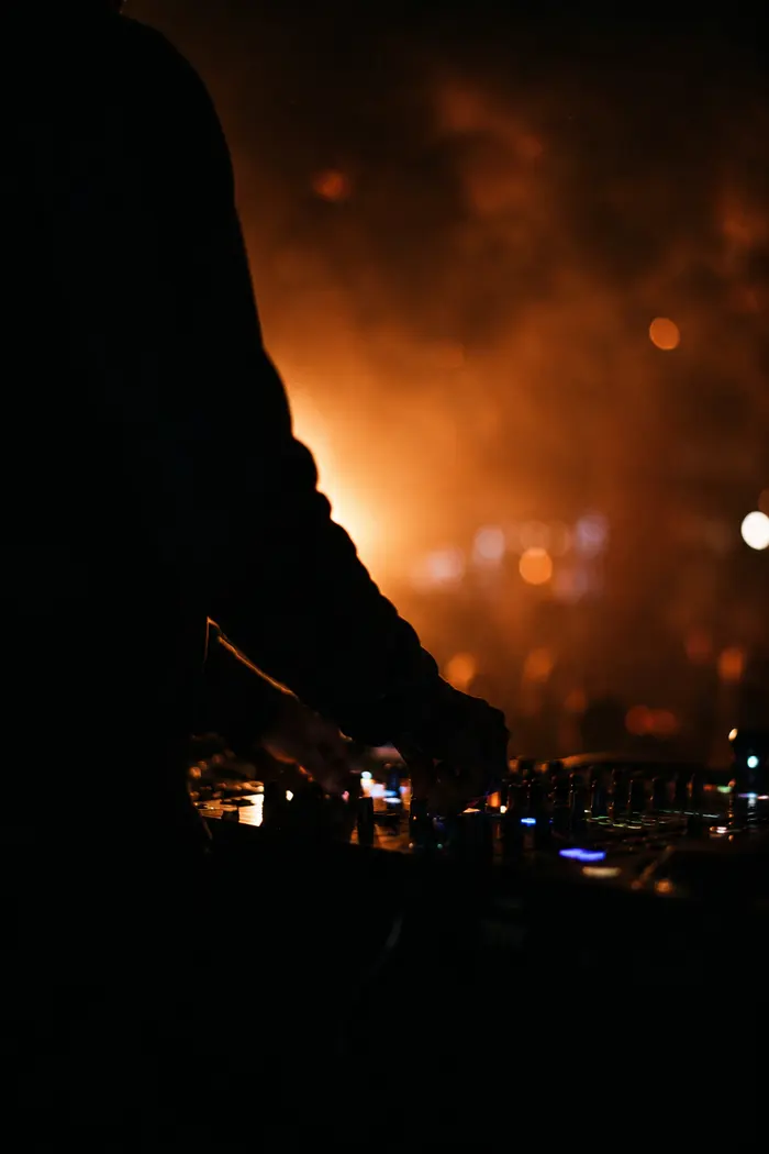 Hände am DJ-Controller im warmen Gegenlicht